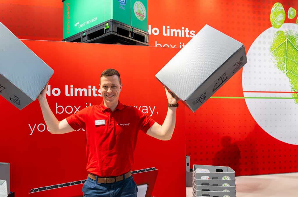 Mitarbeiter mit zwei Faltboxen auf Messestand