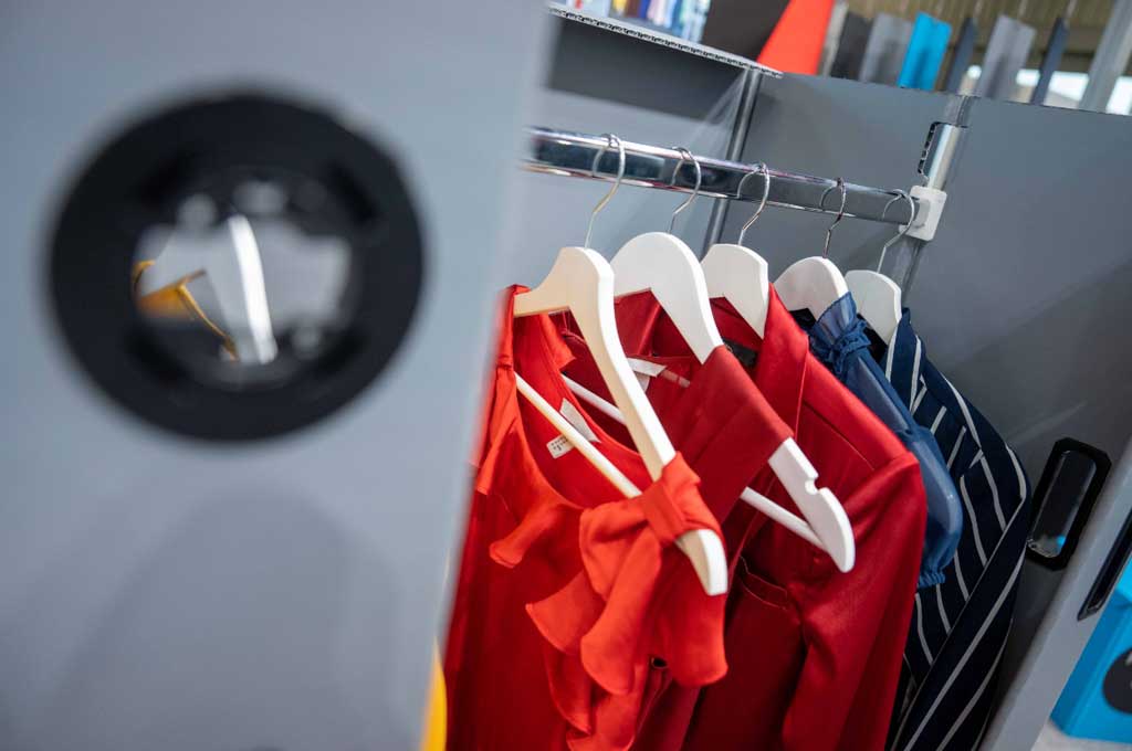 Kleiderstange mit Kleiderbügeln und Kleidung in Container